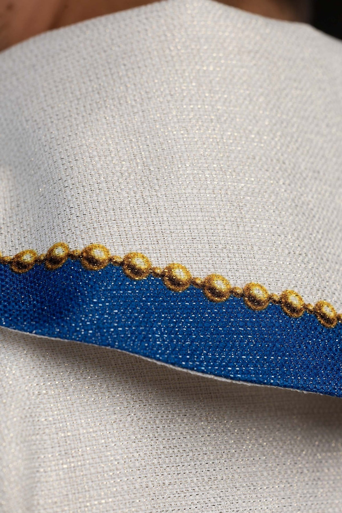 Casula com detalhe lateral da faixa azul, acabamento dourado e tecido marfim ecru