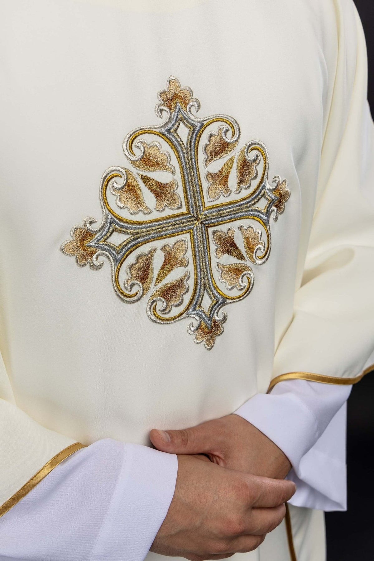 Casula marfim ecru em close-up, com cruz decorada e viés dourado nas mangas