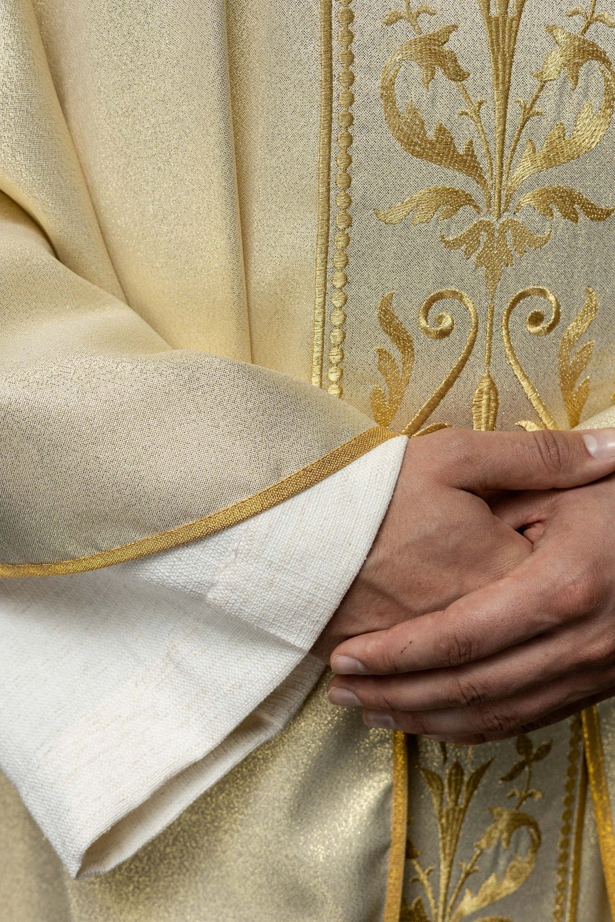 Casula litúrgica marfim em detalhe, com bordado dourado e acabamento dourado na manga