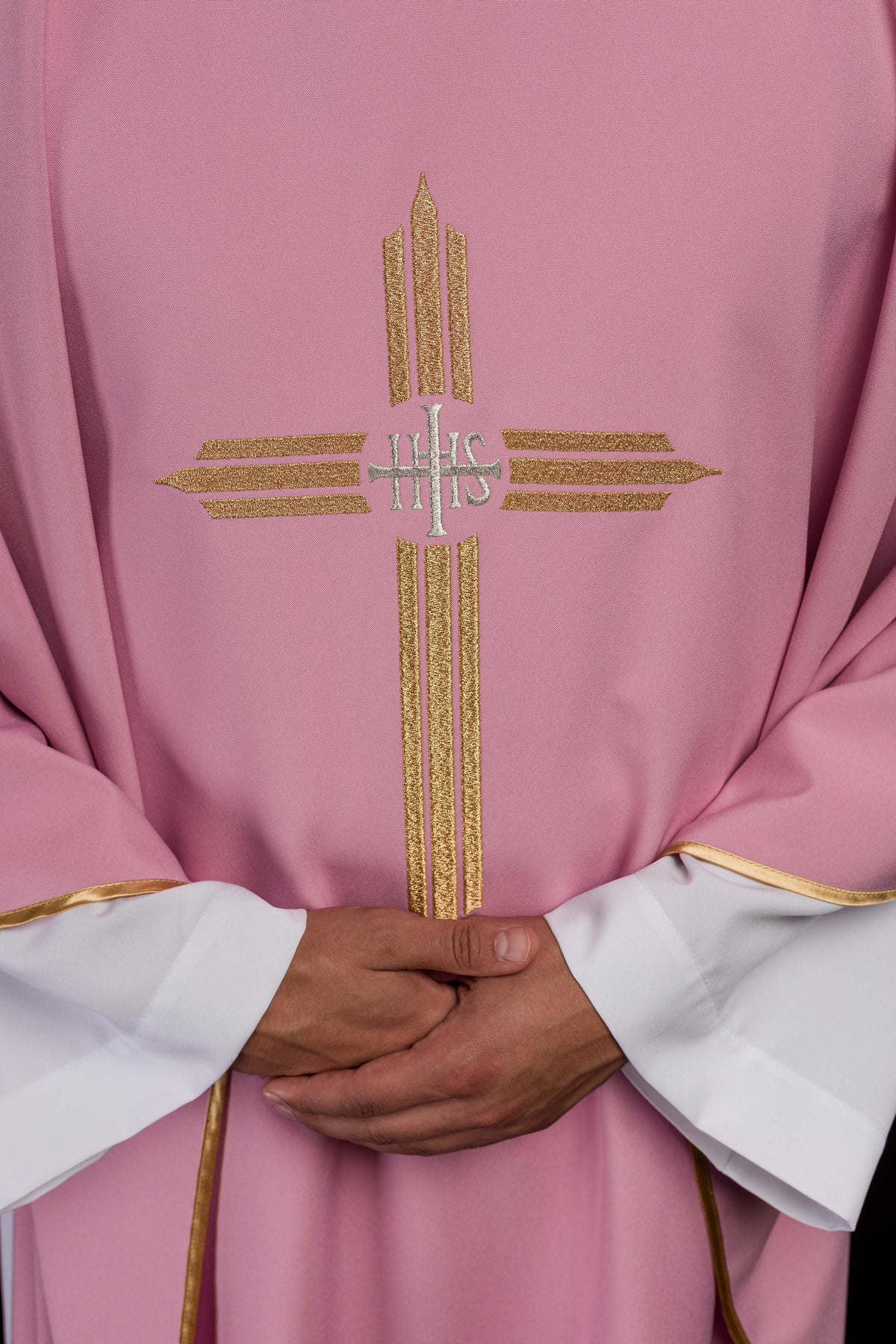 Casula rosa com detalhe aproximado do bordado dourado IHS na frente