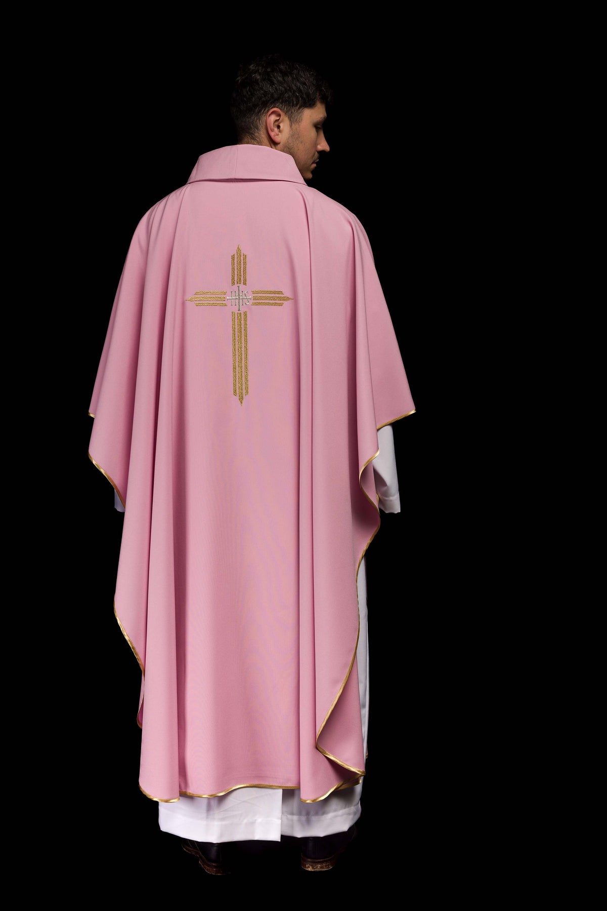 Casula rosa vista de costas em corpo inteiro, com bordado IHS dourado