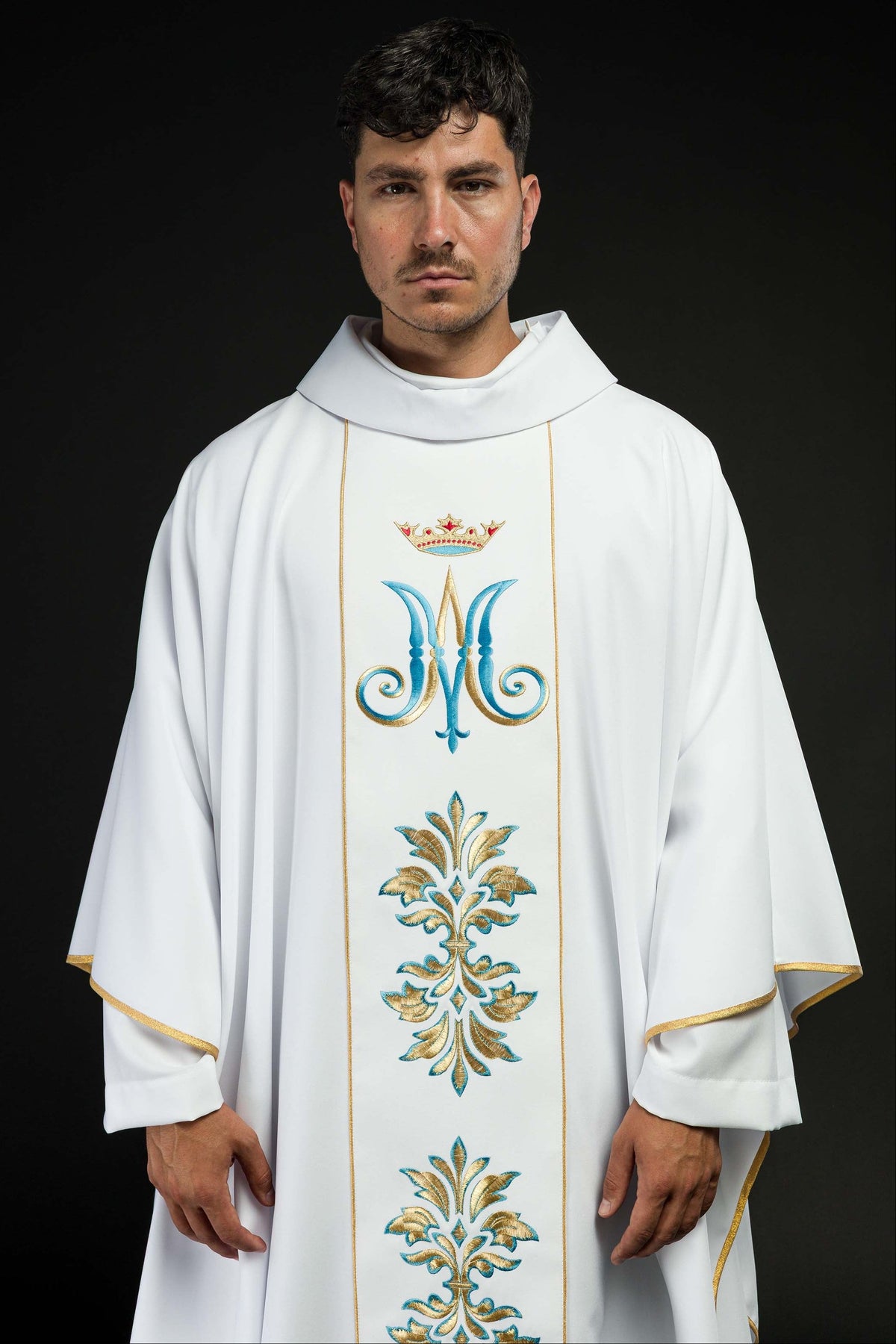 Casula branca com bordado mariano vista de frente, com monograma azul e dourado, coroa e arabescos bordados