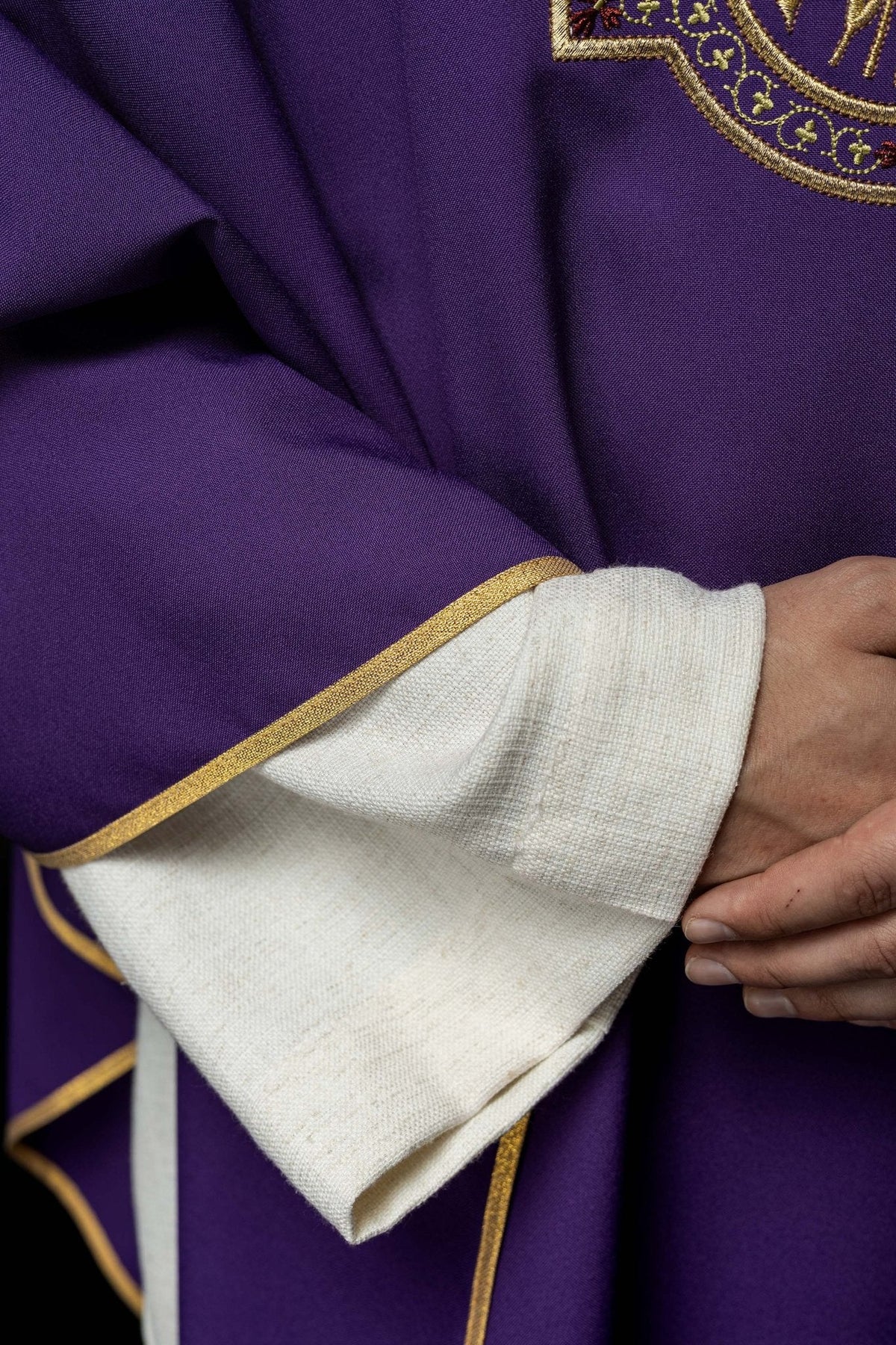 Casula roxa com bordado IHS e PAX, detalhe do tecido roxo e punho branco com galão dourado