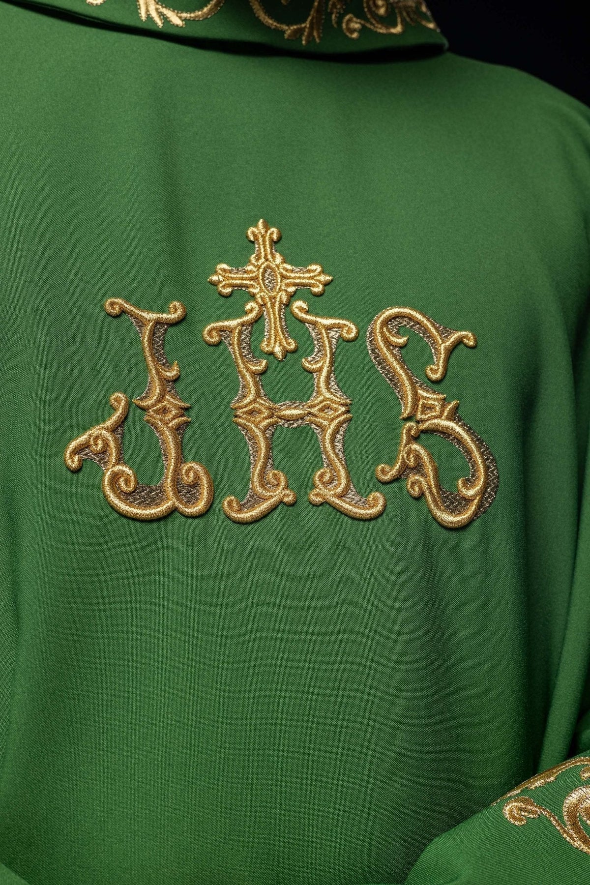 Casula verde com monograma IHS em bordado dourado visto em close-up frontal