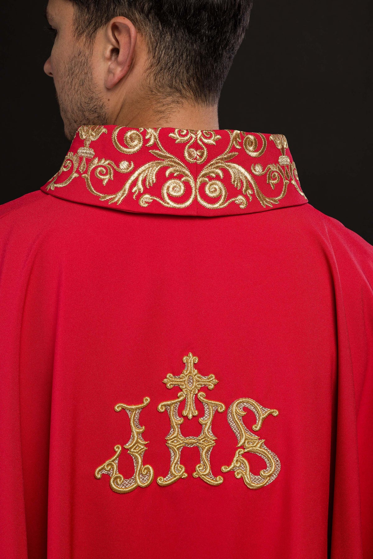 Casula vermelha vista pelas costas, com bordado IHS dourado e gola ornamentada