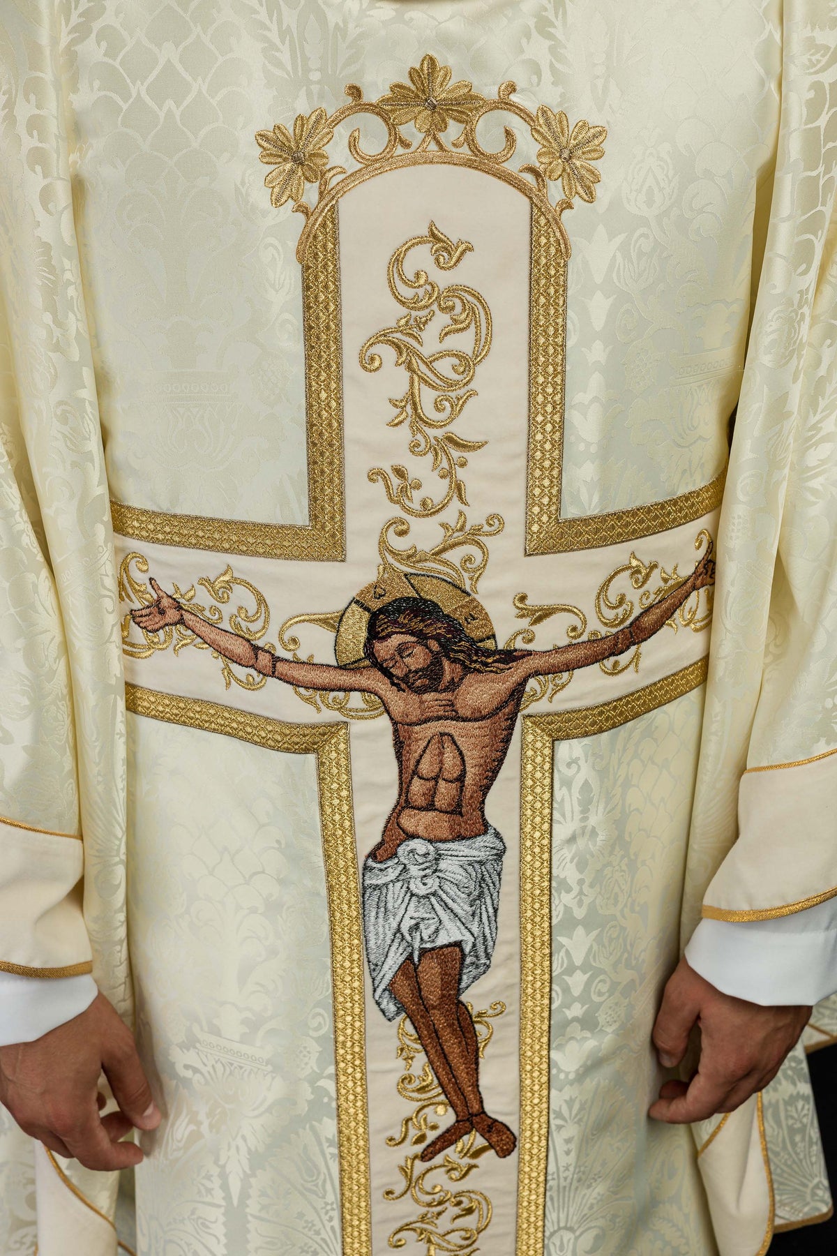 Casula creme em detalhe, com tecido adamascado, cruz e bordados dourados