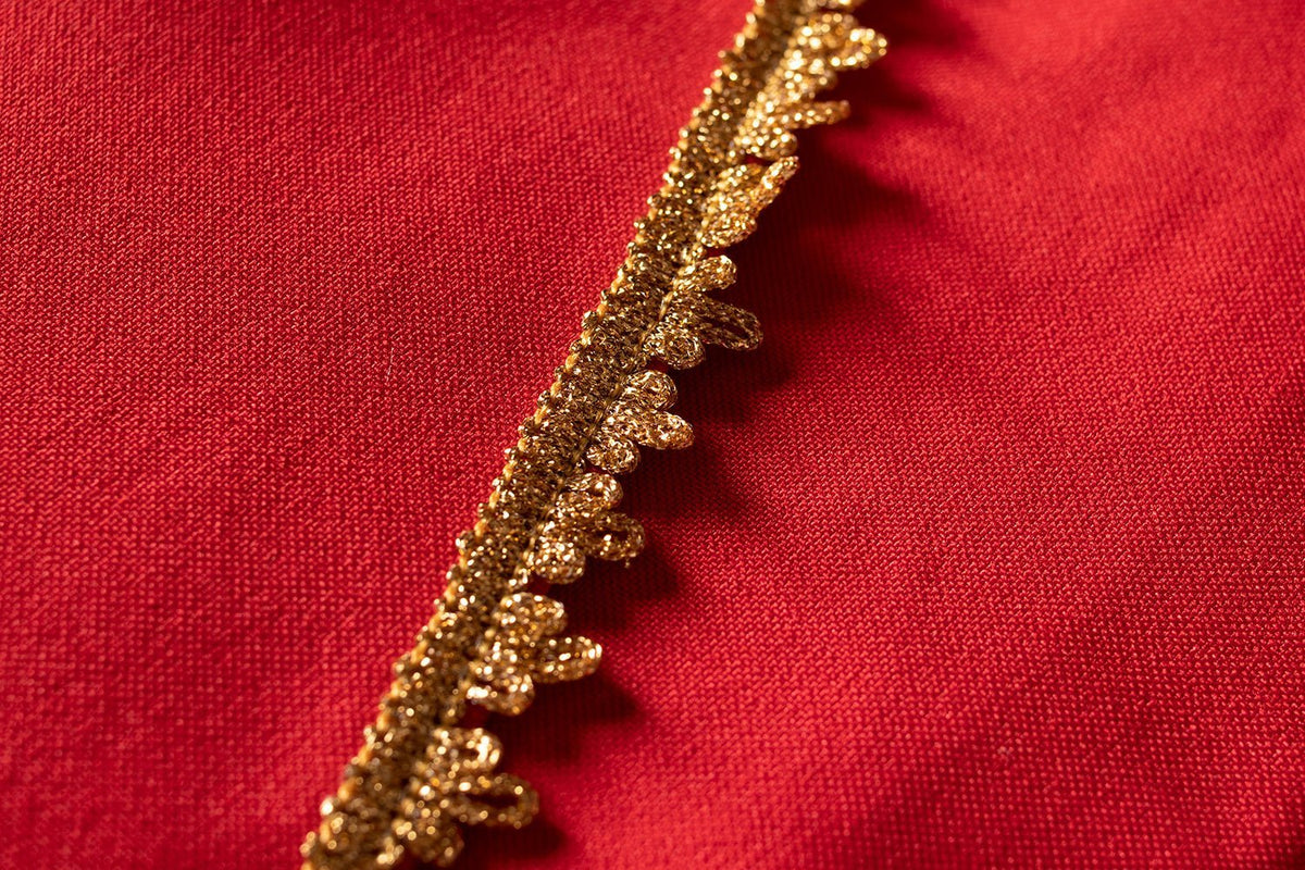 Casula romana vermelha em close-up do acabamento dourado na borda