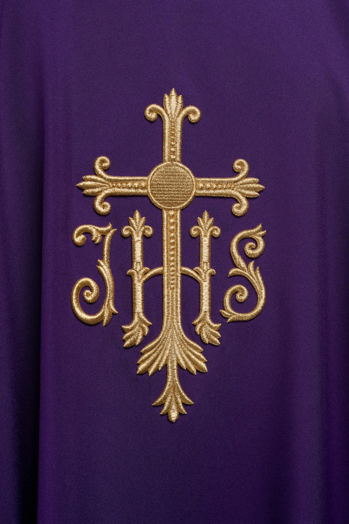 Casula roxa com bordado dourado de cruz e IHS em close-up frontal