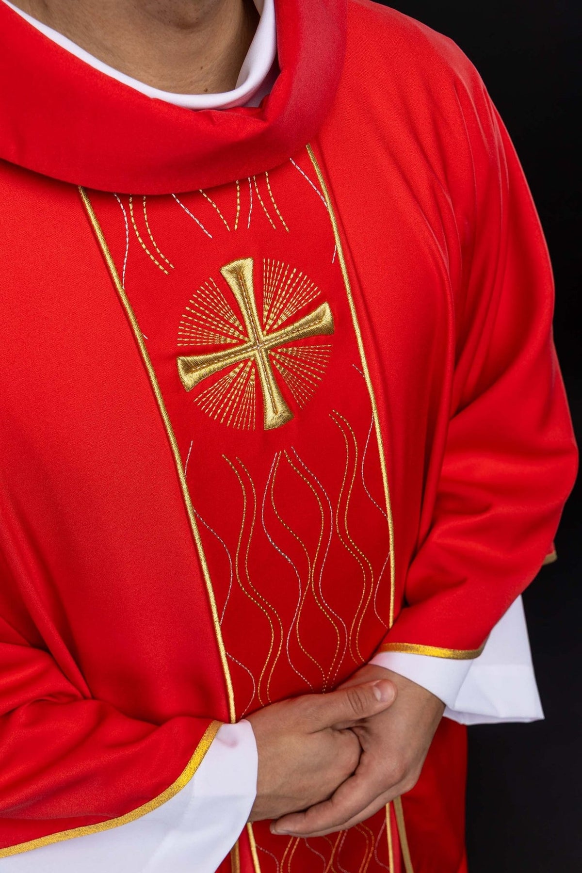 Casula vermelha em close-up frontal, com cruz dourada e bordado em linhas onduladas