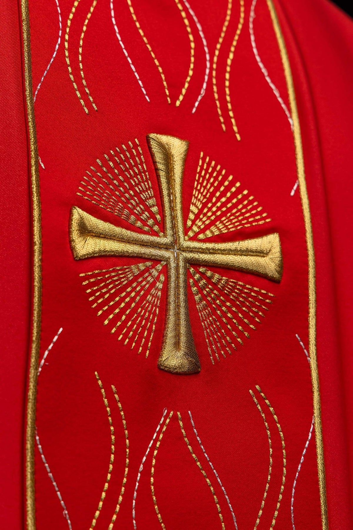 Casula vermelha com close-up da cruz dourada bordada e detalhes radiantes
