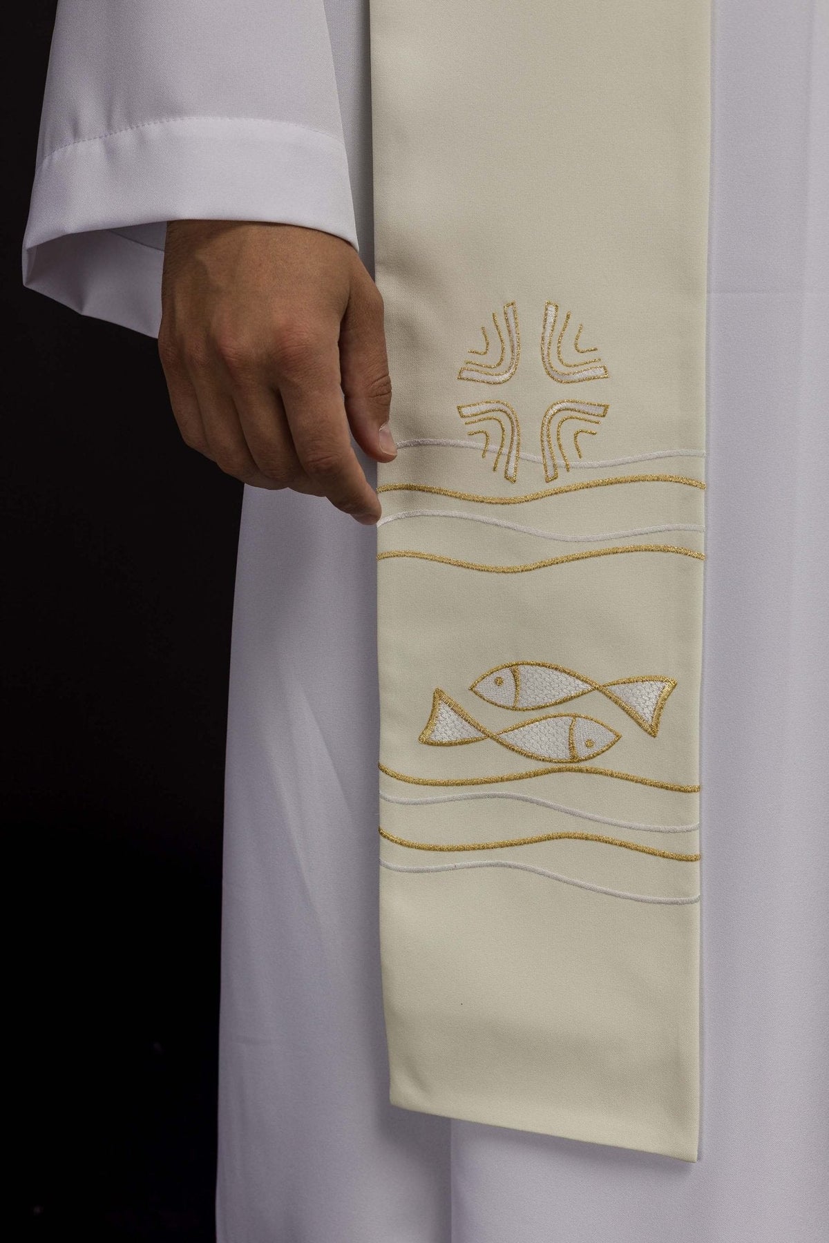 Estola sacerdotal creme em close, com peixes e cruz bordados em dourado e linhas onduladas