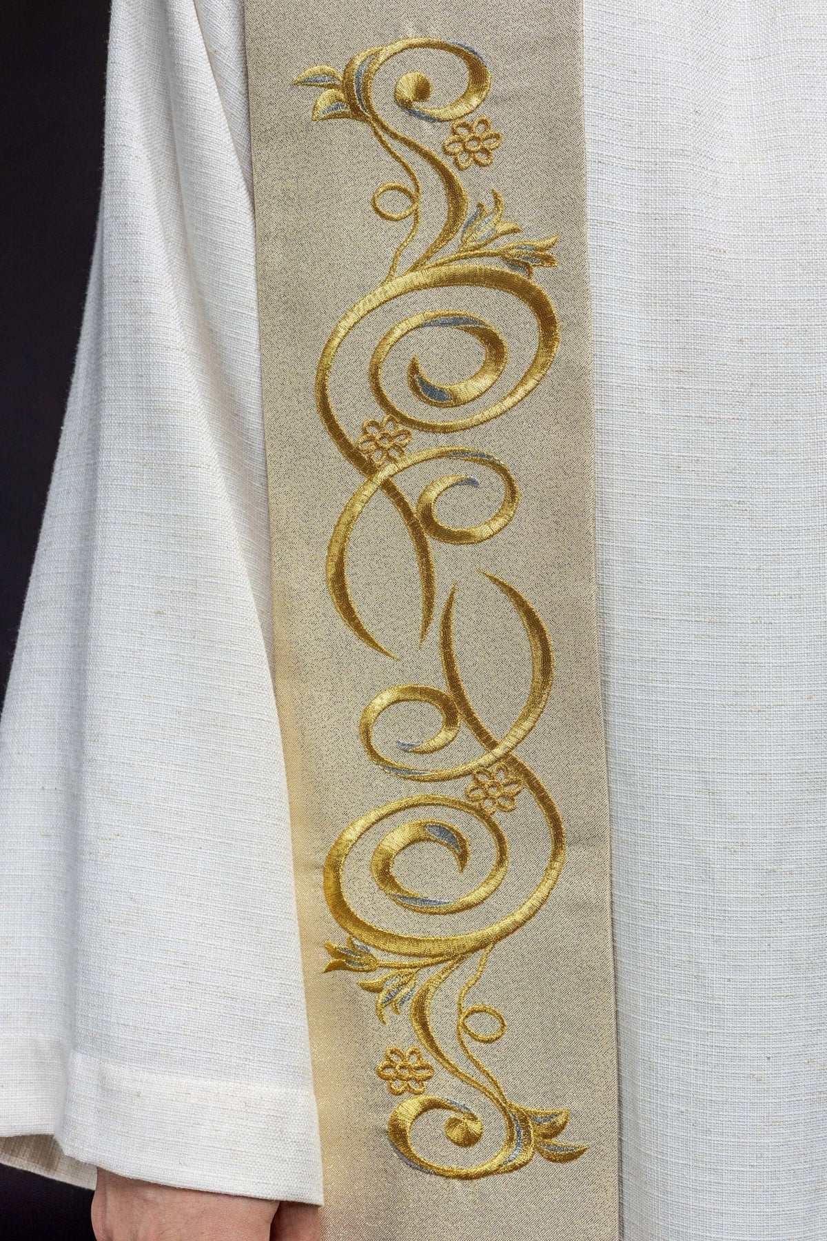 Estola dourada em close-up, mostrando arabescos florais bordados em fio dourado