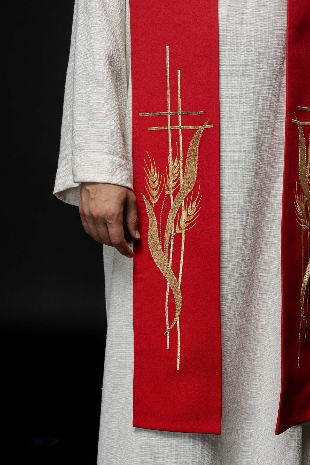 Estola sacerdotal vermelha com close-up do bordado dourado de cruzes e espigas