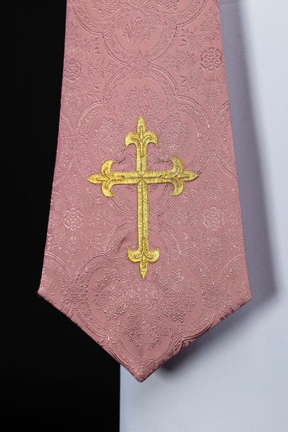 Estola sacerdotal rosa em tecido jacquard com bordado dourado de cruz, close-up da ponta