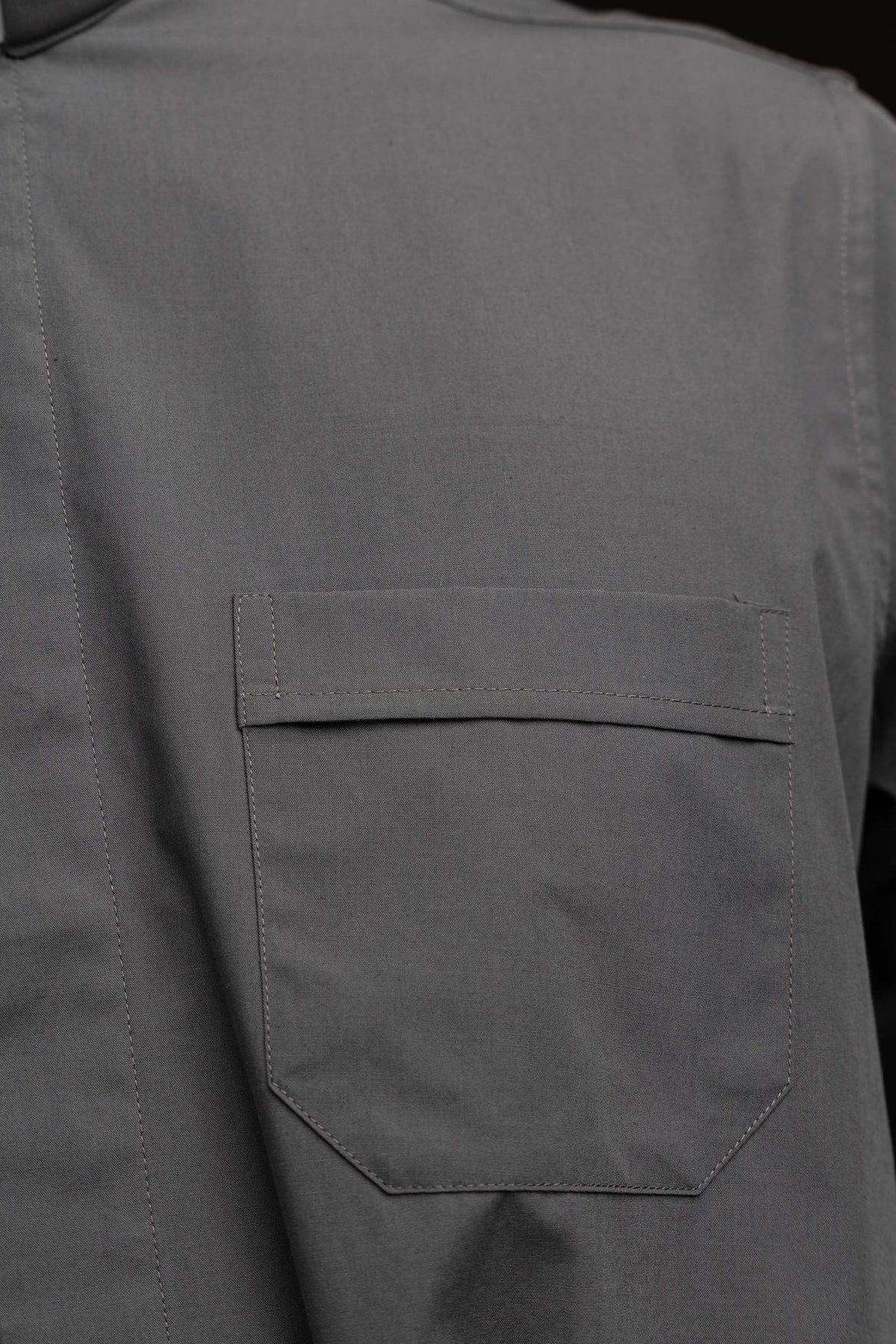 Camisa clerical cinza-escura com close-up do bolso frontal com aba