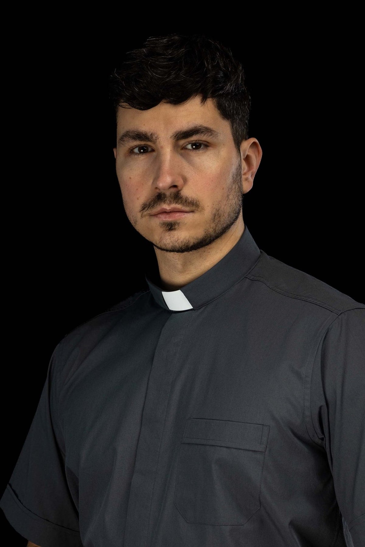 Camisa clerical cinza-escura com colarinho romano e bolso frontal, vista aproximada
