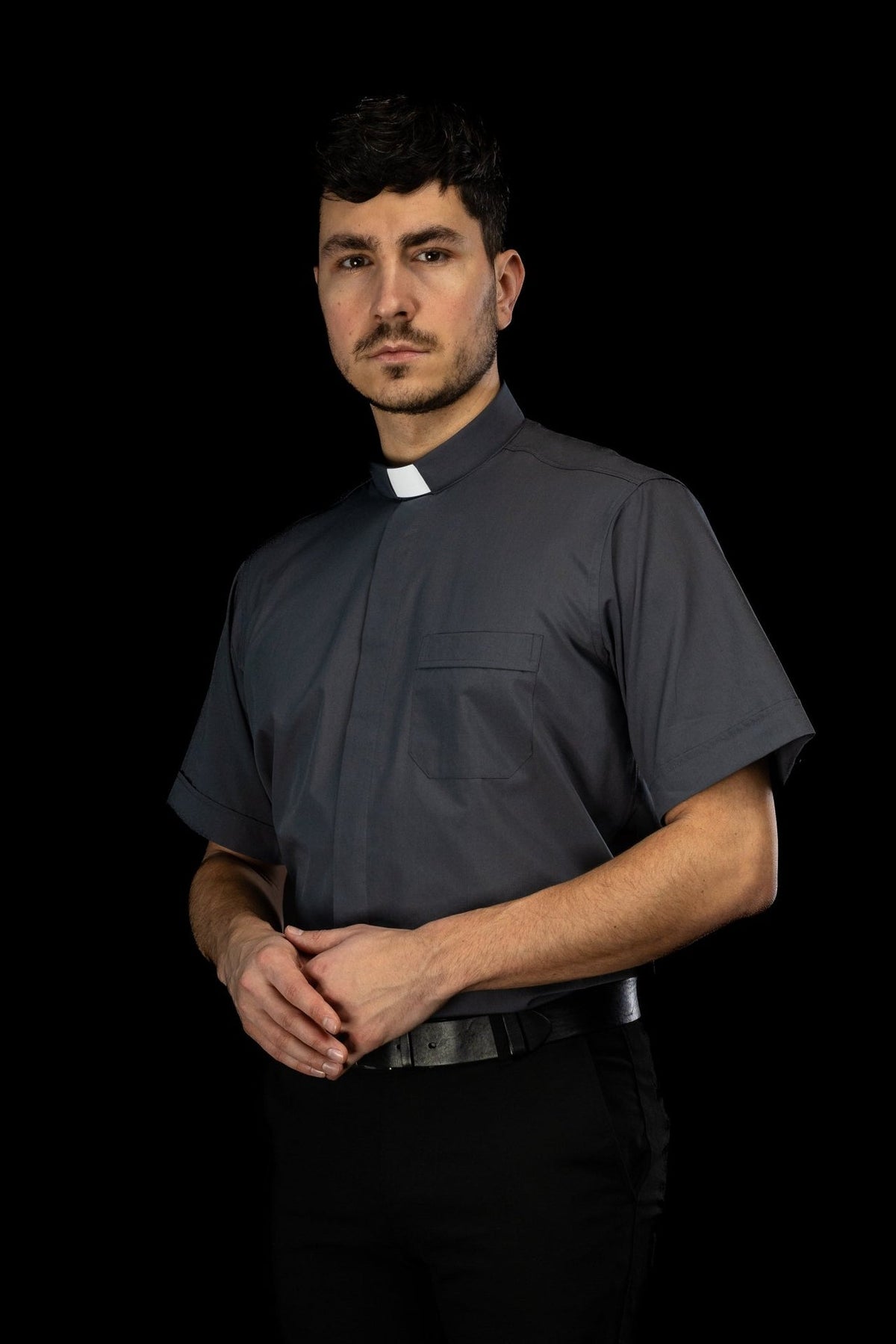 Camisa clerical cinza-escura com vista lateral, bolso frontal e manga curta
