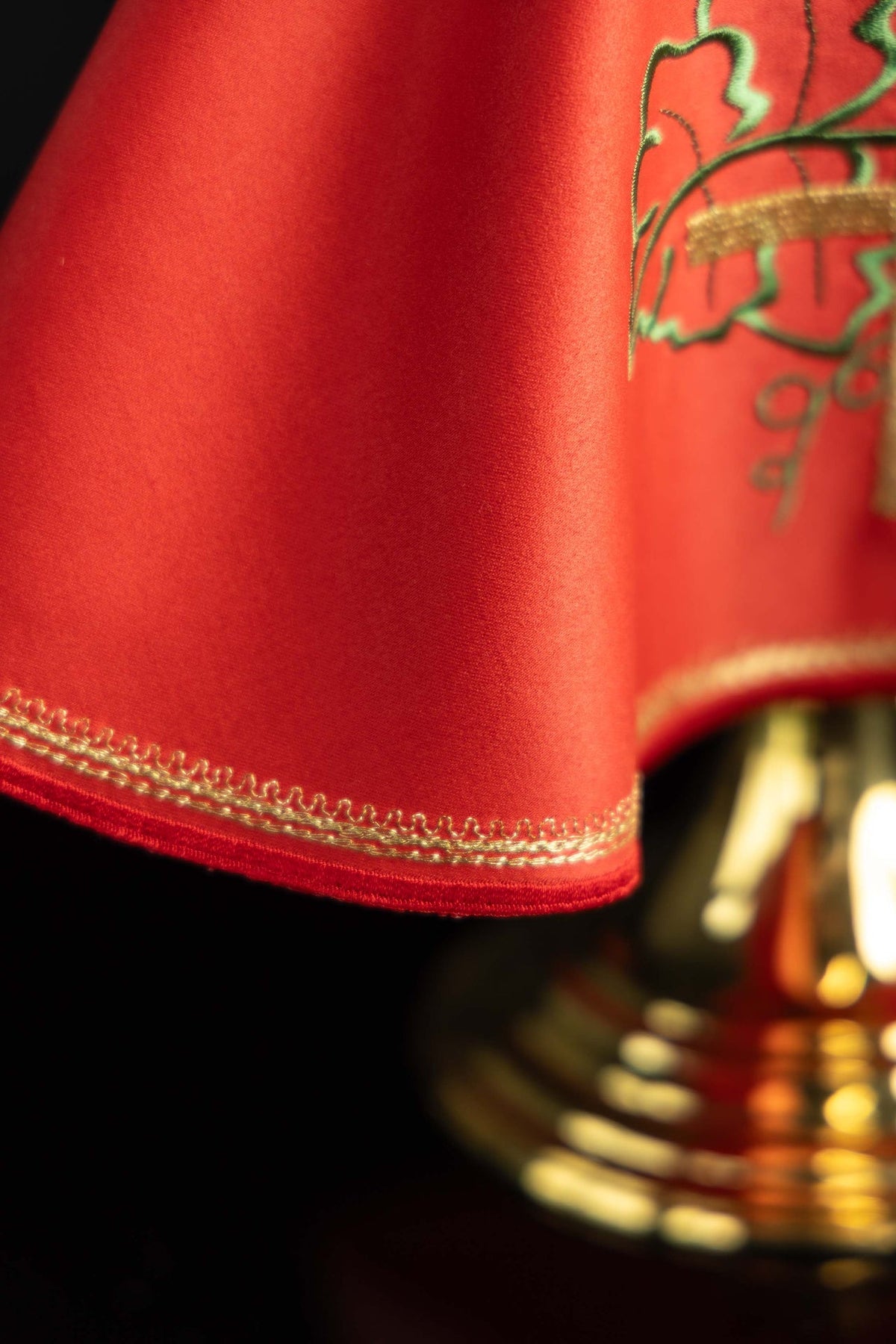 Véu de âmbula vermelho em close-up, detalhe do bordado dourado na barra