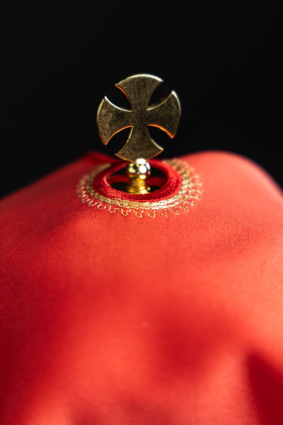 Véu de âmbula vermelho em close-up, detalhe da cruz dourada no topo
