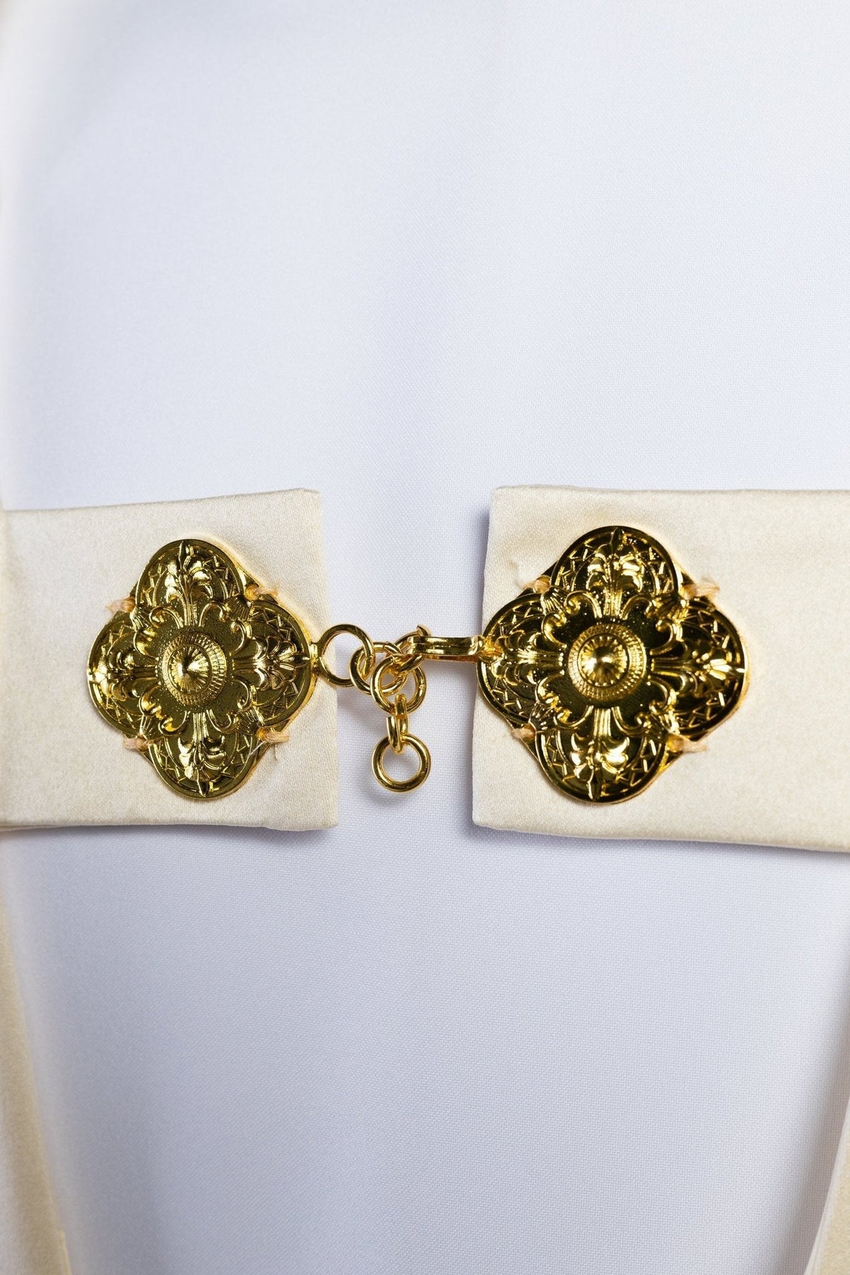 Véu umeral creme, detalhe do fecho dourado com ornamentos florais