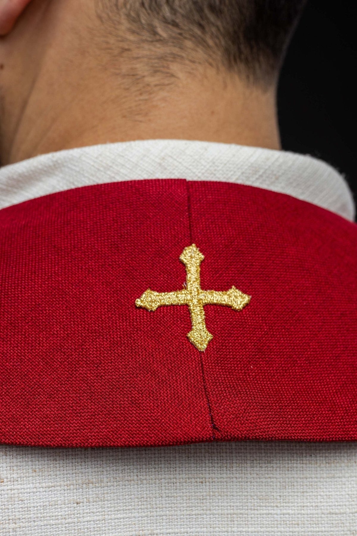 Estola vermelha com close-up da cruz dourada bordada na parte interna
