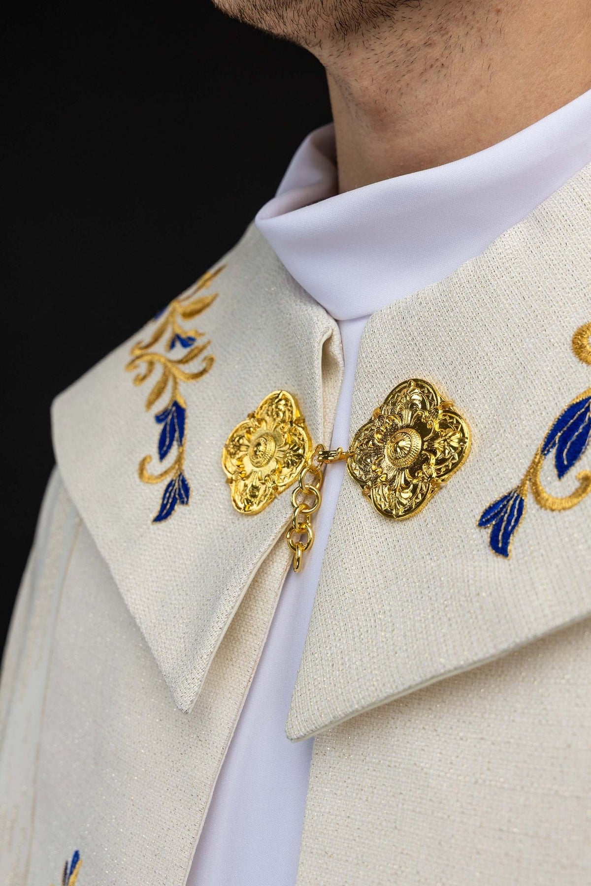 Capa de asperges com close-up do símbolo mariano dourado e coroa bordada