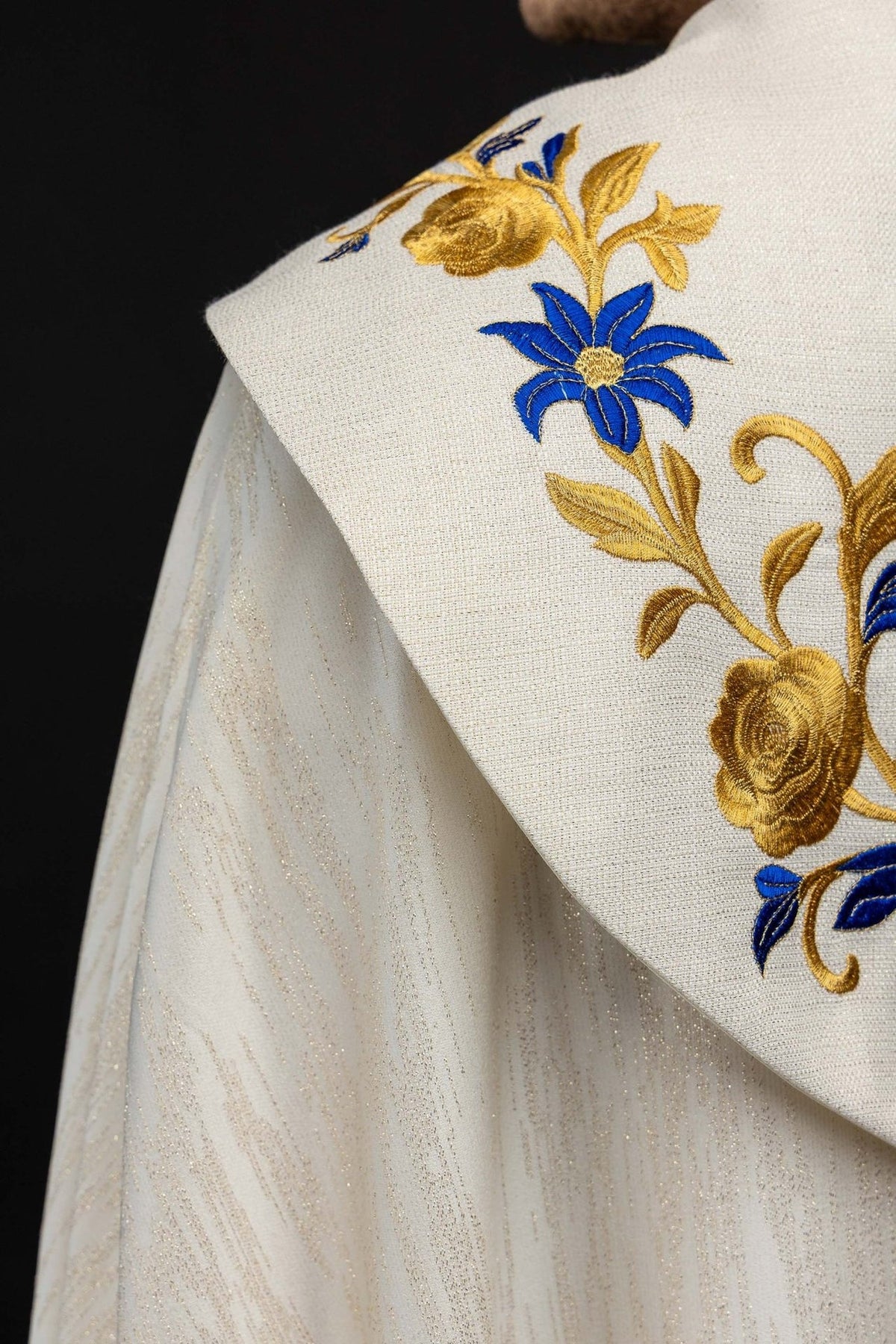 Capa de asperges com close-up do bordado floral azul e dourado no ombro
