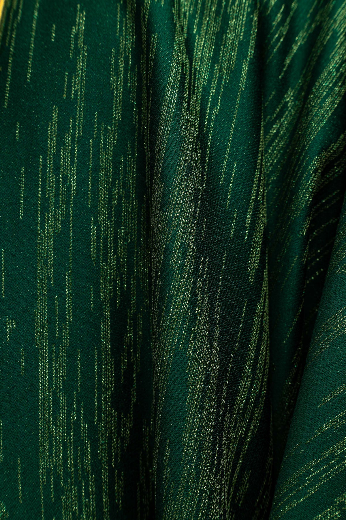 Casula verde com close-up do tecido verde com fios dourados