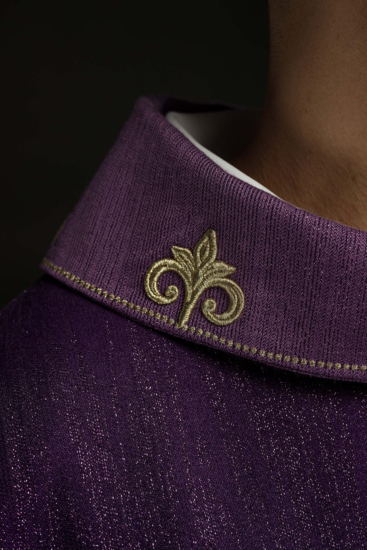 Casula roxa em close-up da gola, com bordado dourado ornamental