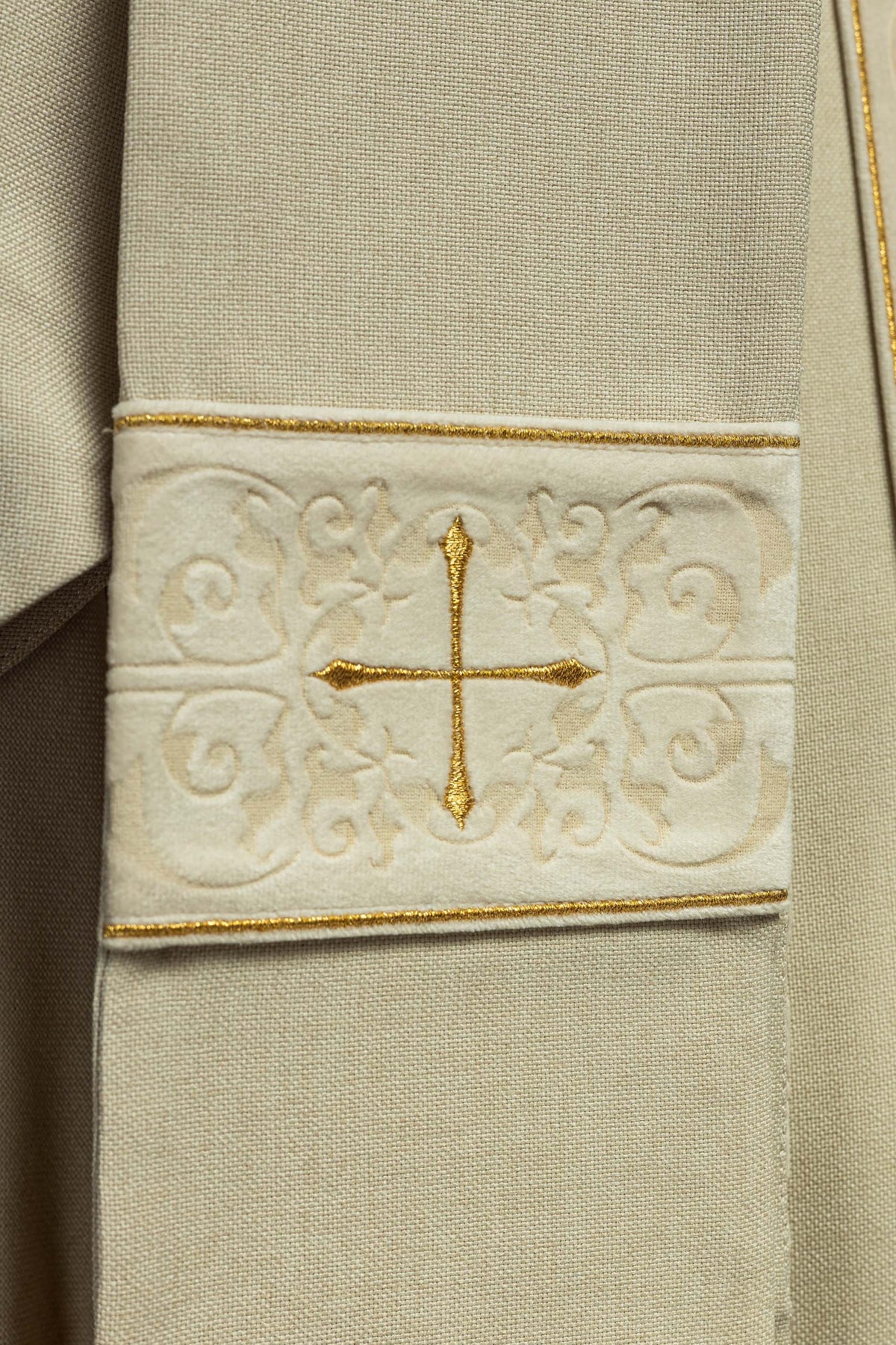 Casula creme com detalhe da aplicação de cruz dourada na manga
