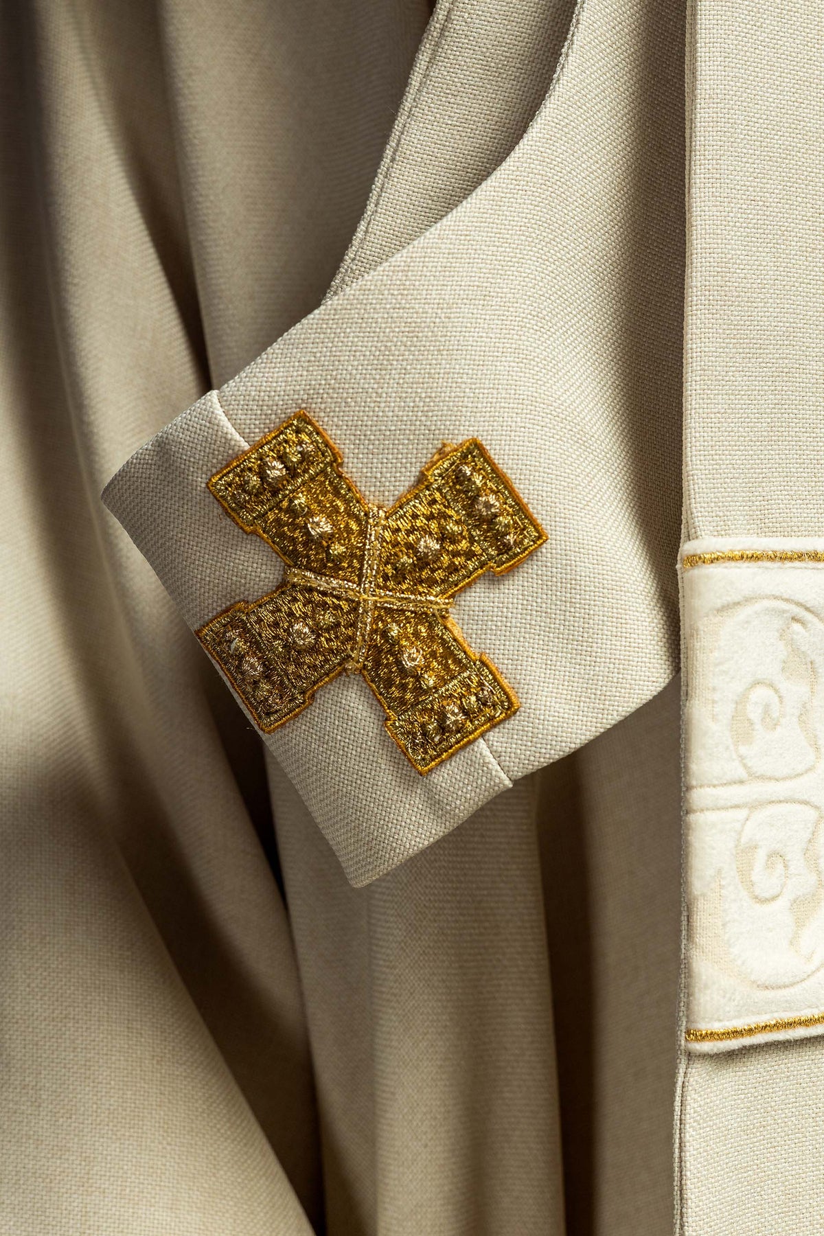 Casula creme com detalhe das borlas douradas pendentes na faixa