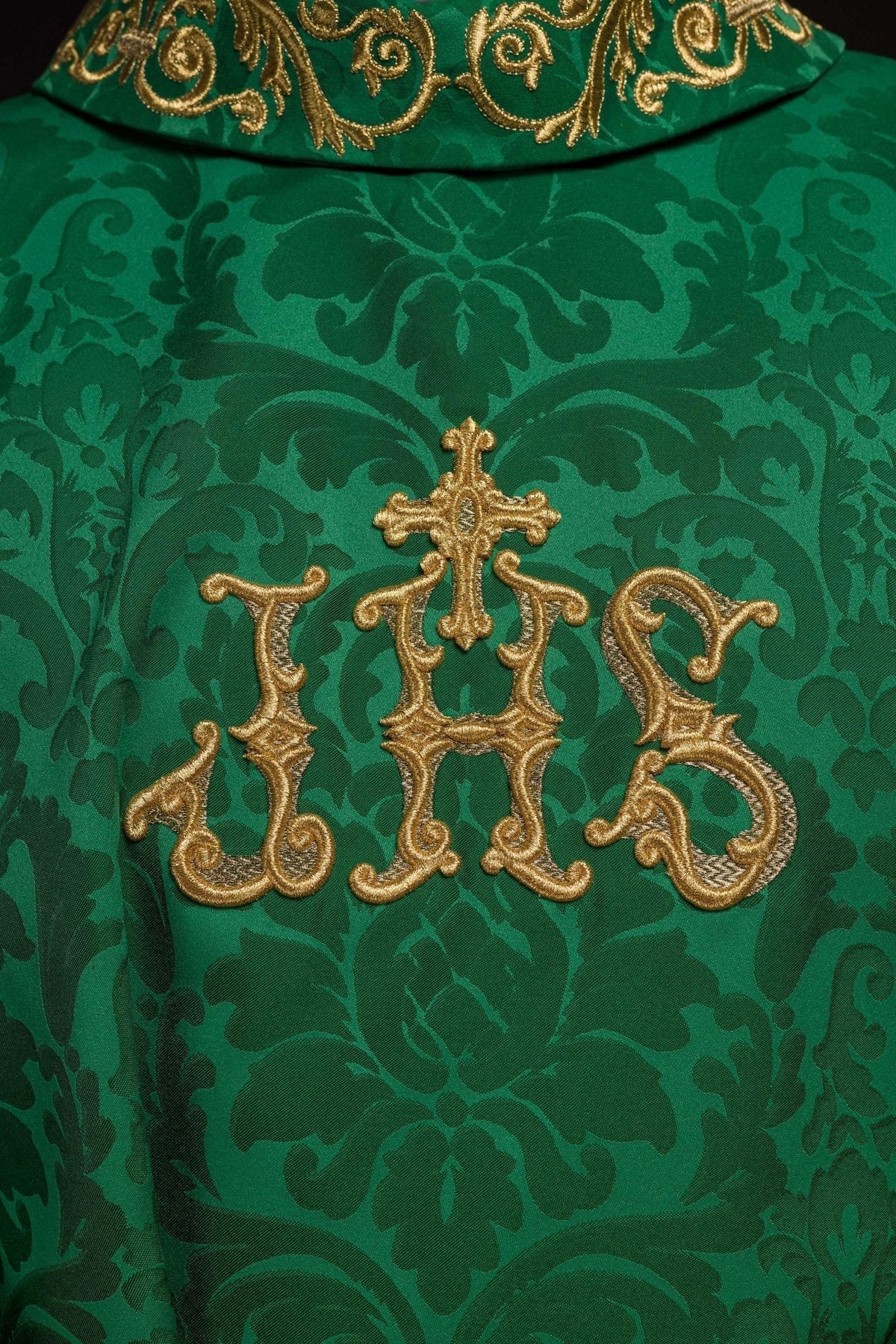Casula verde ornamental, close do bordado IHS dourado com cruz