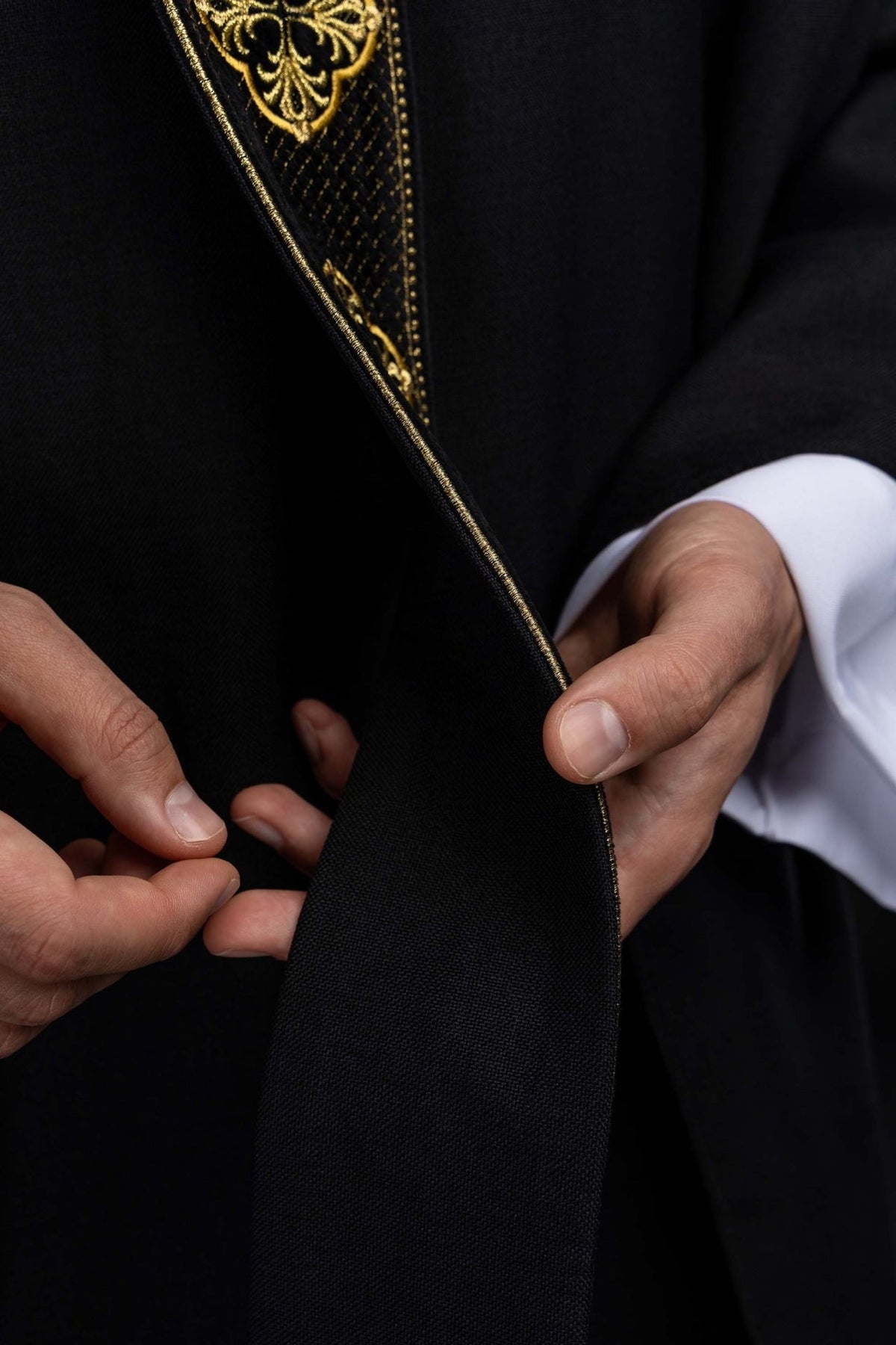 Casula preta com faixa bordada, detalhe do tecido e galão dourado