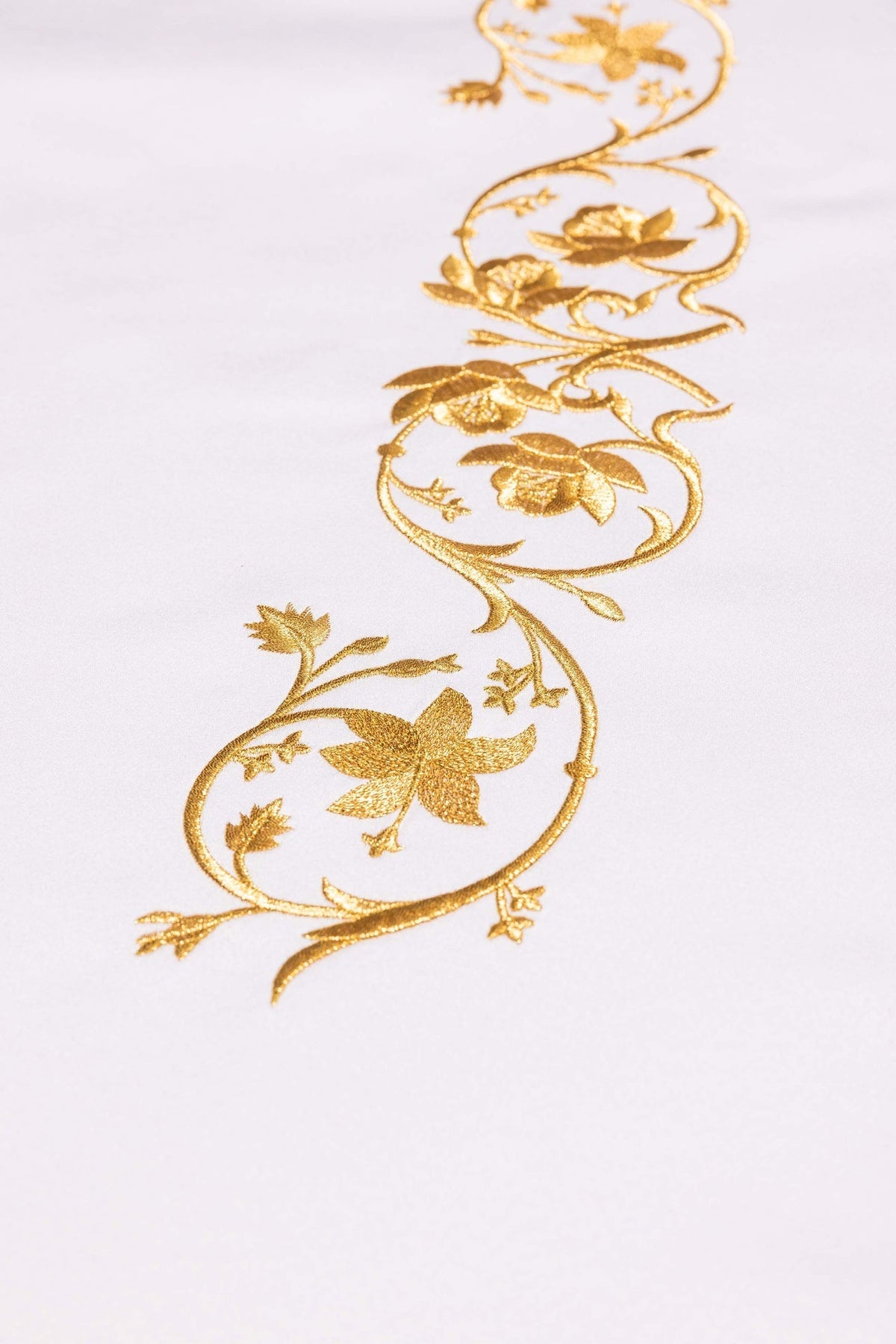 Toalha de altar branca em close-up, com detalhe floral bordado em dourado